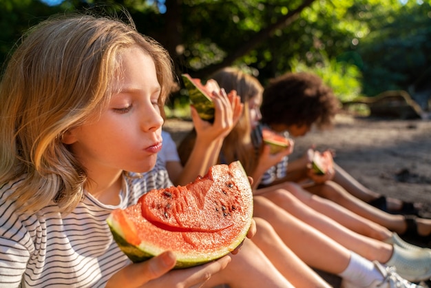 Free photo side view kids eating watermelon