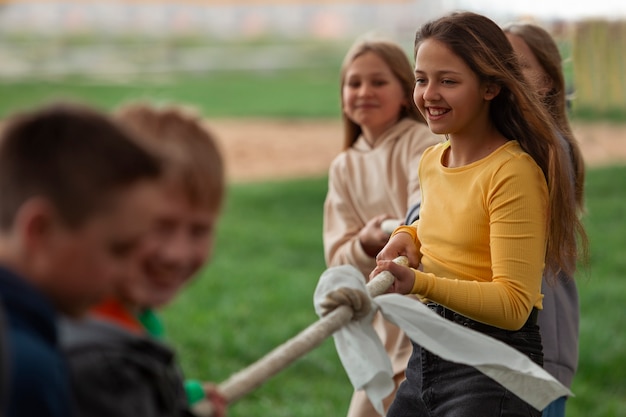 Side view kids playing tug-of-war in the park