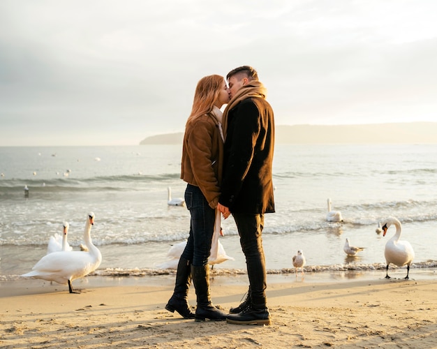 Free photo side view of kissing couple by the beach in winter