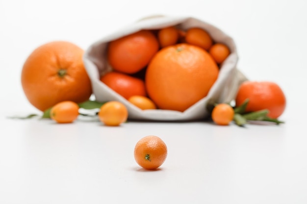 Side view of kumquat with orange tangerine kumquat in sack on white background