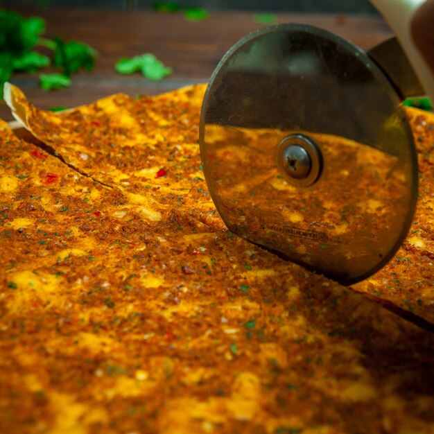 Side view lahmacun with pizza cutting knife and parsley