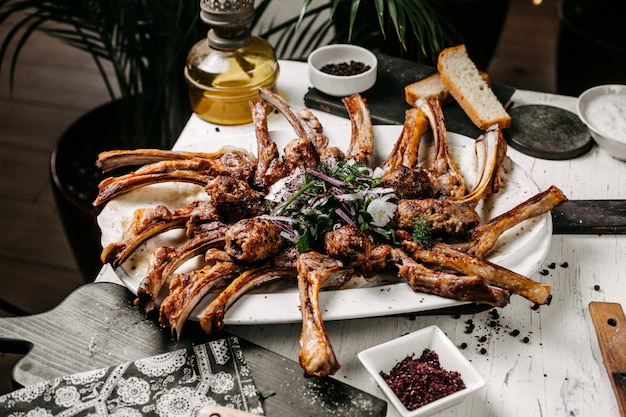 Free photo side view of lamb kebab served with red onion herbs and sumakh on the table