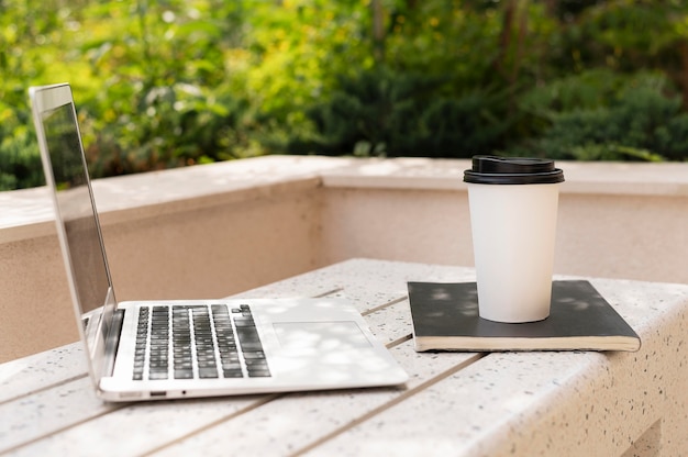 Free Photo side view of laptop with coffee cup outdoors