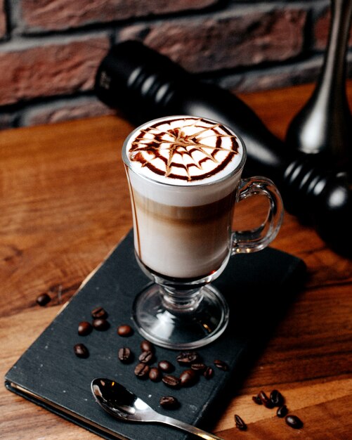 Side view of latte macchiato coffee in glass on wooden table