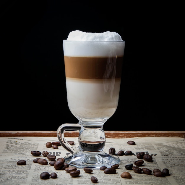 Side view latte with coffee beans in old newspaper