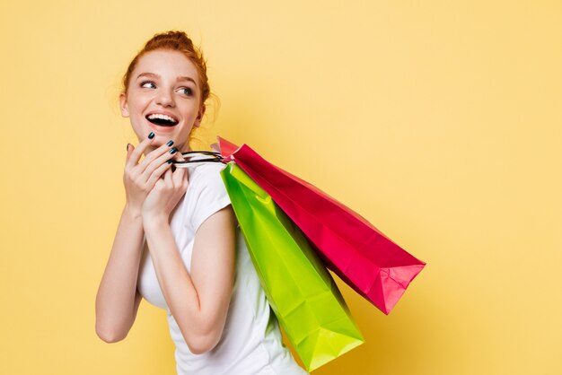 Side view of laughing ginger woman holding packets on shoulder