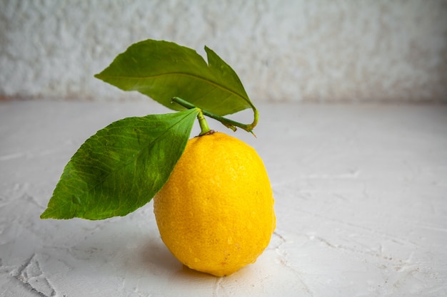 Free photo side view lemon with leaves on white textured background. horizontal