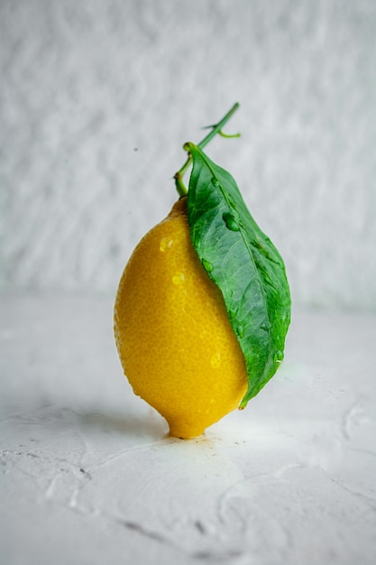 Free Photo side view lemon with leaves on white textured background. vertical