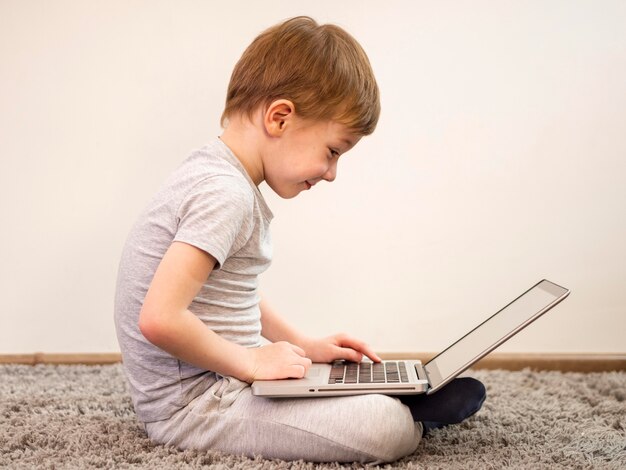 Side view little boy playing on his laptop