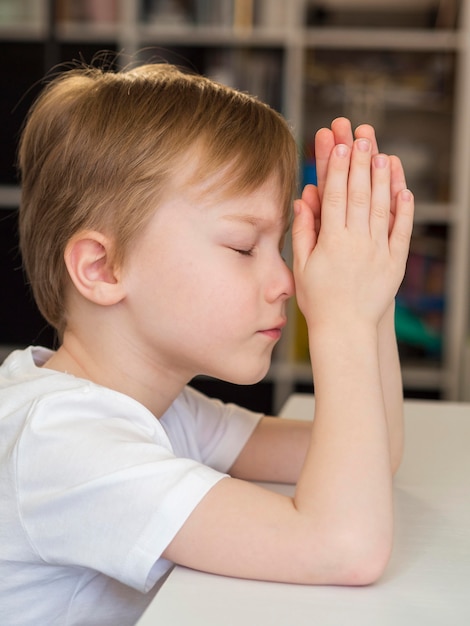 Free photo side view of little boy praying