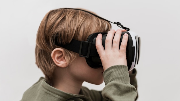 Free photo side view of little boy using virtual reality headset