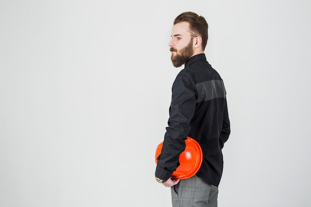 Side view of male architect holding hardhat isolated over white background