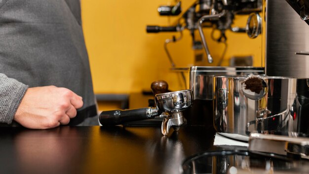 Side view of male barista with apron next to coffee machine