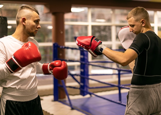 Side view of male boxer practicing with trainer