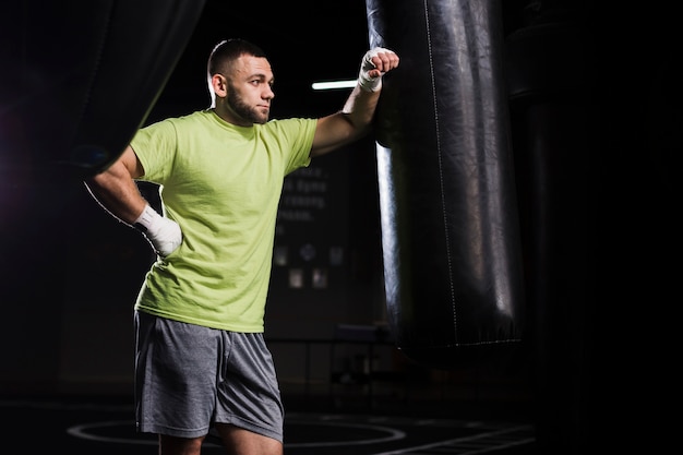 Free Photo side view of male boxer in t-shirt with punching bag