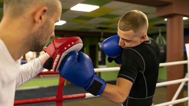 Side view of male boxer with trainer next to ring