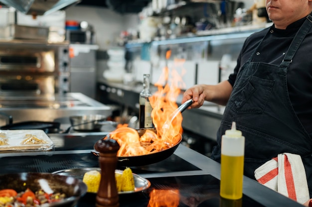 Side view of male chef flambeing dish