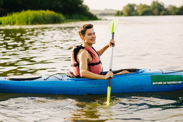 Free photo side view of male kayaker kayaking on lake