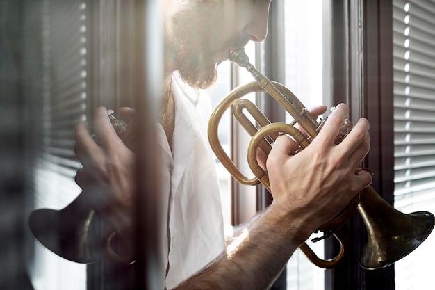 Side view of male musician playing cornet in the window