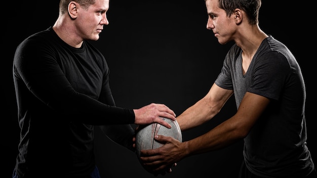 Side view of male rugby players holding ball