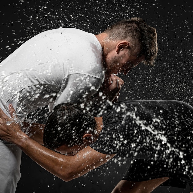 Free Photo side view of male rugby players with ball and water splashes