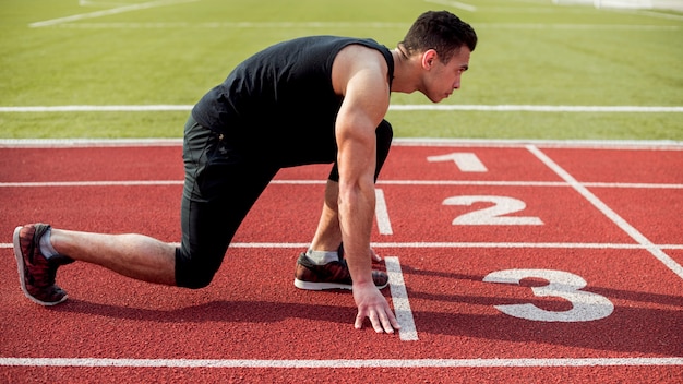 Free photo side view of male runner sprinter getting ready to start the race