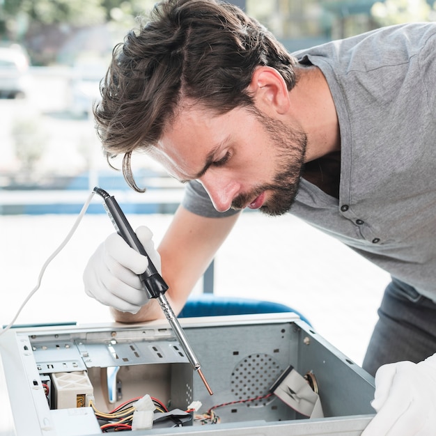 Free photo side view of a male technician repairing computer cpu in workshop