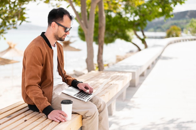 Side view of man at the beach working on laptop