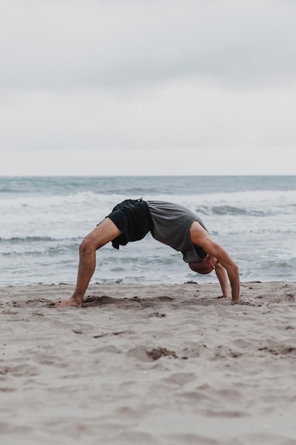 Side view of man on the beach in yoga position