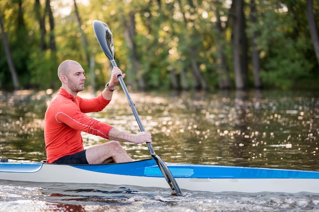 Side view man in canoe with paddle