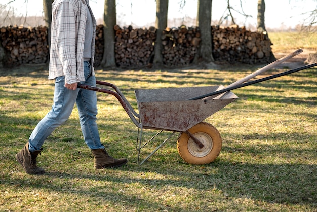 Free photo side view man carrying wheelbarrow