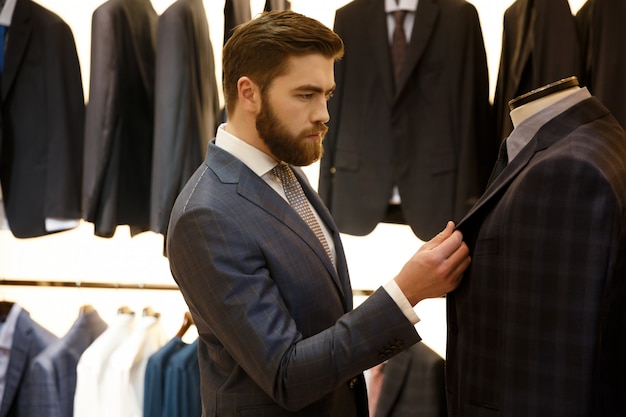 Free photo side view of man choosing a jacket in shop