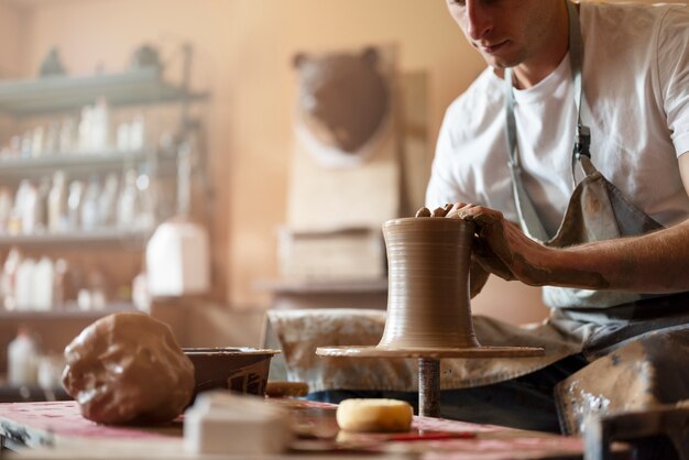 Side view man doing pottery indoors