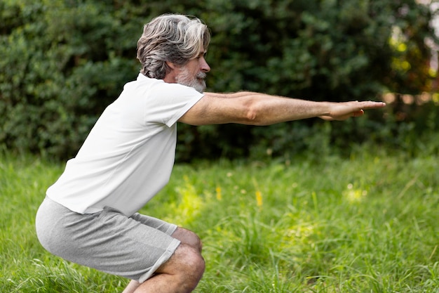 Free Photo side view man doing squats outdoors