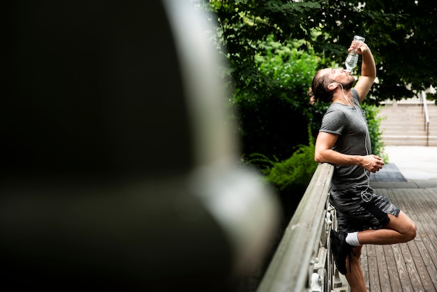 Free Photo side view of man drinking water in park