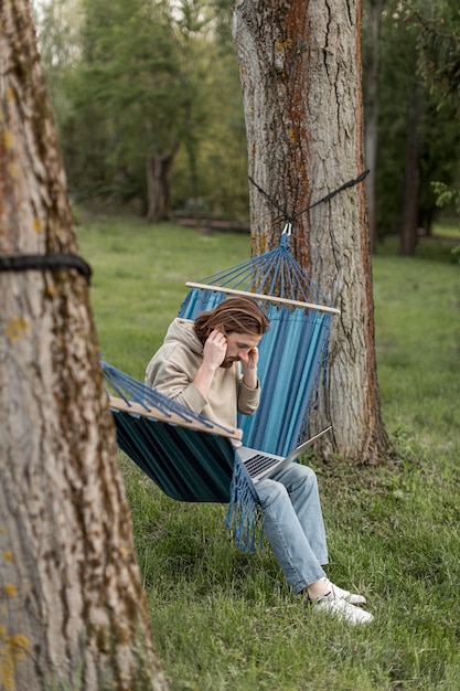 Free photo side view of man in hammock in nature