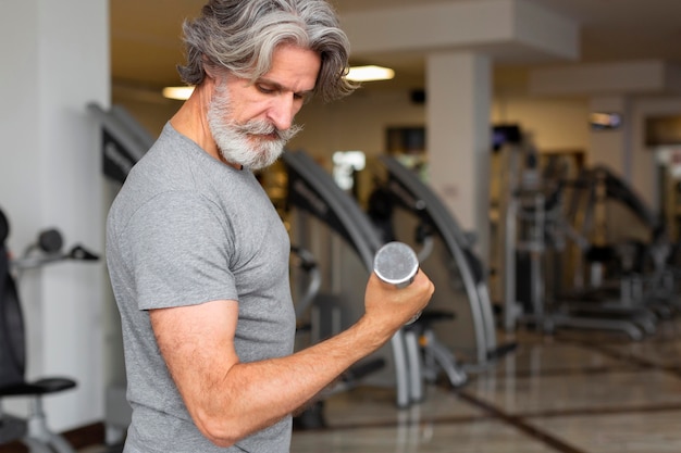 Free photo side view man holding dumbbell