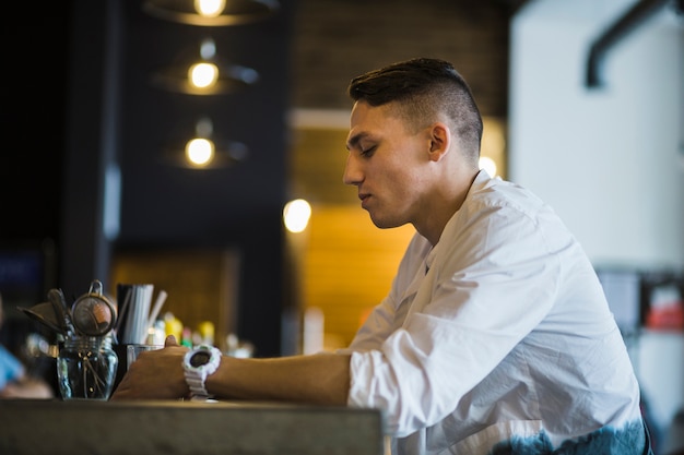 Free photo side view of a man holding glass of drink in the restaurant