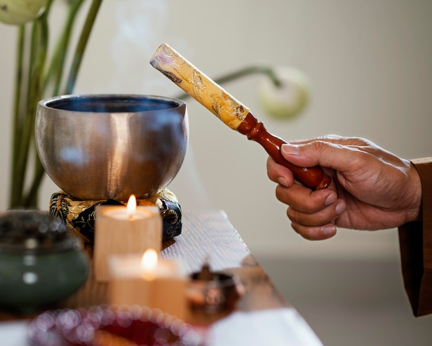 Free photo side view of man holding object for prayer with candles and bowl