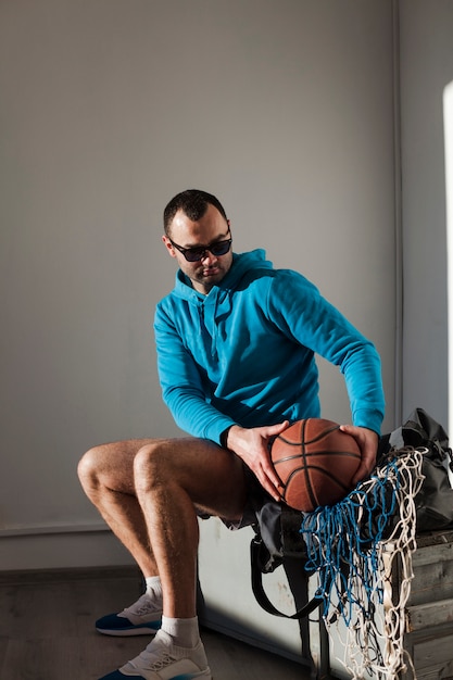 Free photo side view of man in hoodie holding basketball