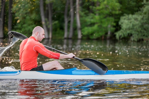 Side view man in kayak with paddle