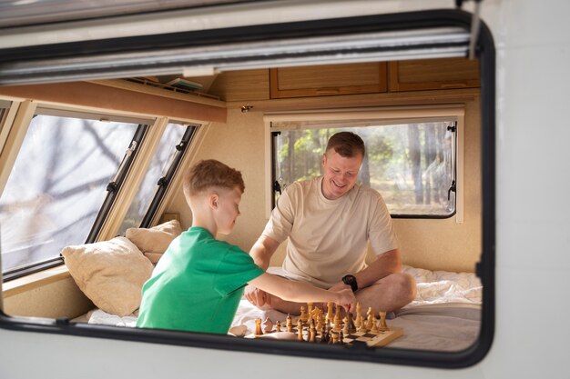 Side view man and kid playing chess