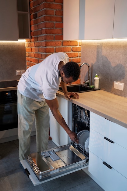 Side view man loading the dishwasher