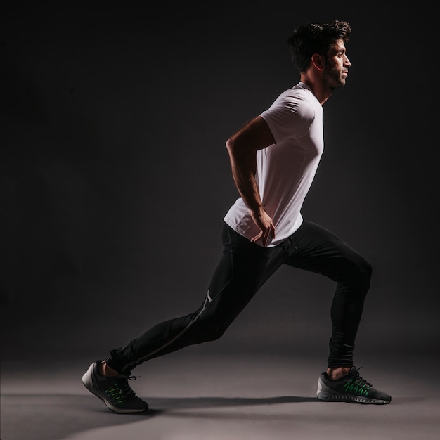 Free photo side view man lunging on dark background