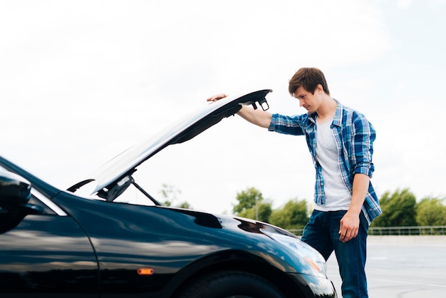 Side view of man opening car hood