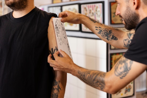 Free photo side view man placing tattoo