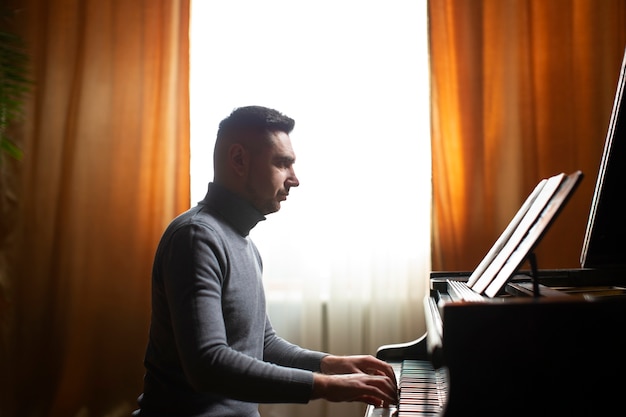 Free photo side view man playing piano