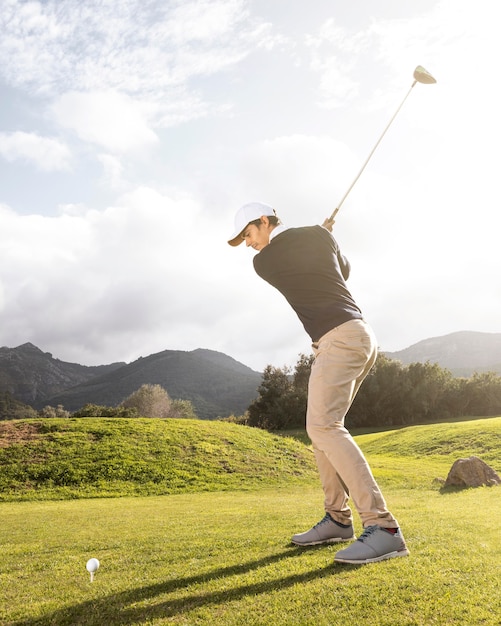 Side view of man practicing golf on the field