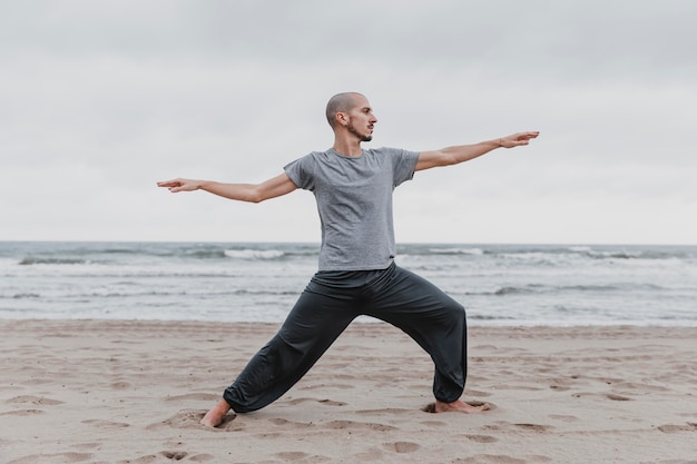 Side view of man practicing yoga positions outdoors