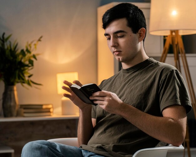 Side view of man reading the bible on the chair